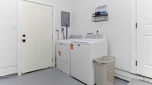 A laundry room with a washer and dryer, a utility box, and a laundry basket.