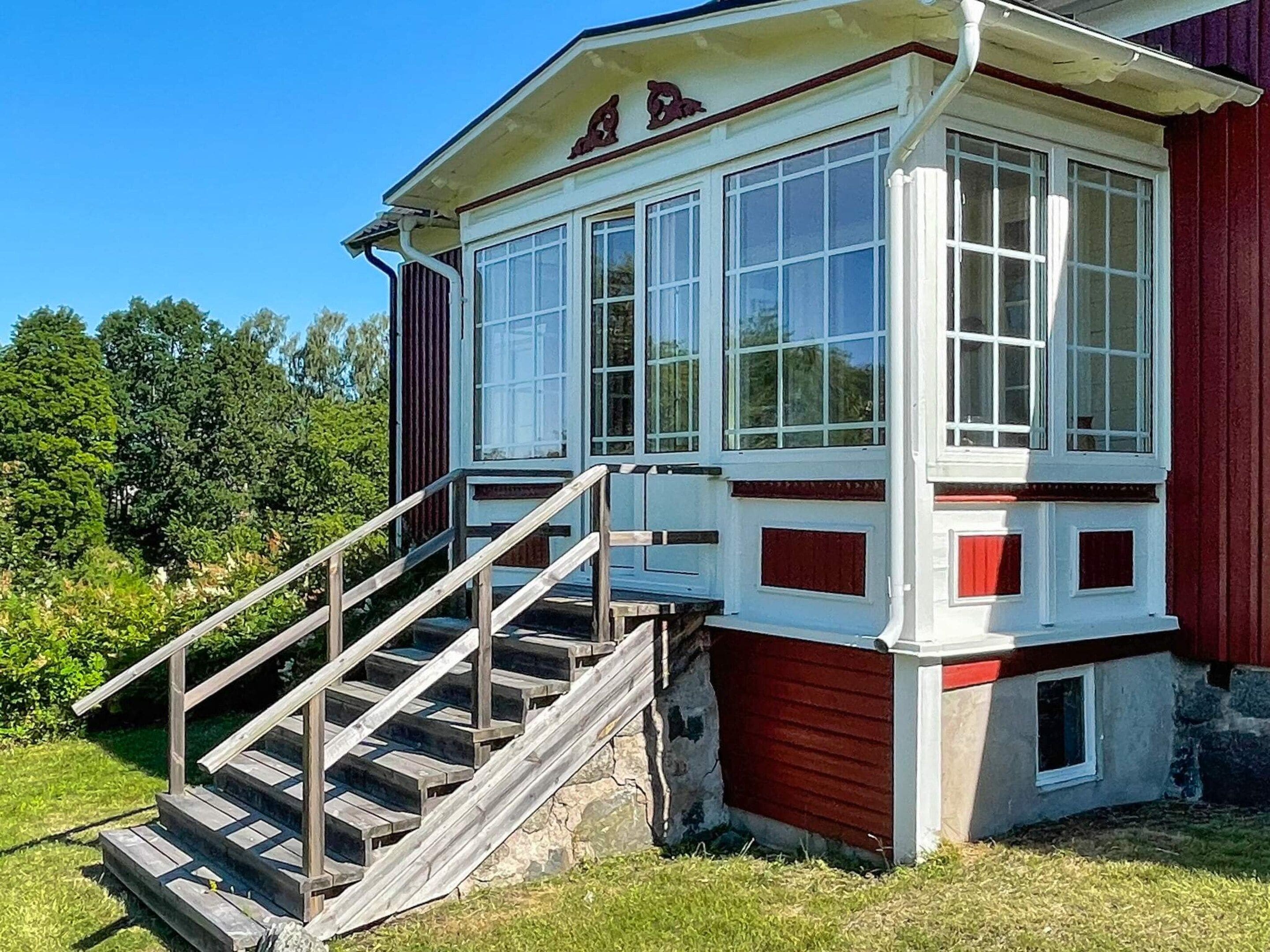 A building with a staircase leading to a windowed porch area.