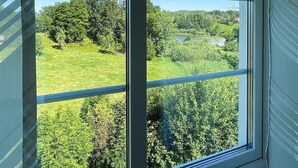 A window with a view of a green landscape, including trees and a body of water. - 8 Person Holiday Home in Kristdala (Kristdala)
