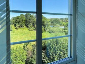 A window with a view of a green landscape, including trees and a body of water. - 8 Person Holiday Home in Kristdala (Kristdala)