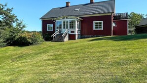 A red building with a porch, a chimney, and a small balcony. - 8 Person Holiday Home in Kristdala (Kristdala)
