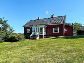 A red building with a porch, a chimney, and a small balcony. - 8 Person Holiday Home in Kristdala (Kristdala)