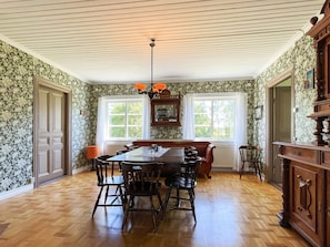 A dining room with a wooden table and chairs, a chandelier, and floral wallpaper. - 8 Person Holiday Home in Kristdala (Kristdala)