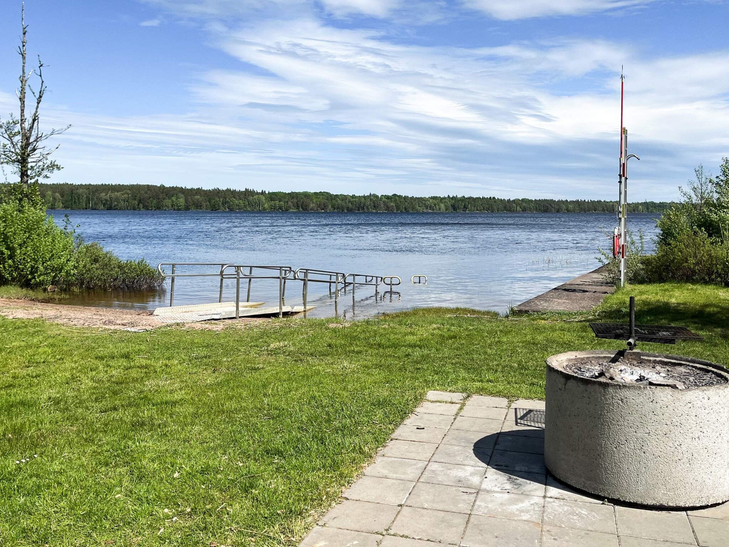 A lakeside walkway with a metal railing, a concrete planter, and a clear view of the lake.