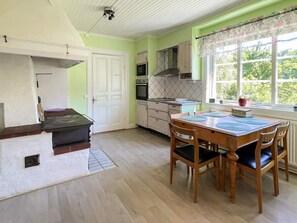 A kitchen with a dining table and chairs, a stove, cabinets, and a window with a view of greenery. - 8 Person Holiday Home in Kristdala (Kristdala)