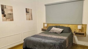 Une chambre à coucher comprenant un lit, des tables de chevet, un banc et des œuvres d’art abstraites accrochées au mur.