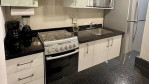 Une cuisine équipée d’une cuisinière, d’un four à micro-ondes, d’un réfrigérateur et d’un évier.