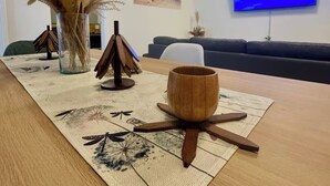Une table à manger agrémentée d’un set de table en fibres tressées, d’un saladier en bois et de petits supports décoratifs en bois.