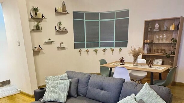 Un canapé modulable doté de tiroirs de rangement, une table à manger, des chaises et des étagères murales ornées d’objets décoratifs.