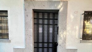 Une entrée d’immeuble avec un portail en métal, le numéro « 49 » sur le mur et une petite fenêtre sur la gauche.