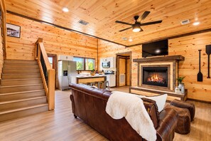 A wooden interior with a fireplace, a sofa, a television, and a kitchen area. - Waterfront: Hot tub, pool table, river, fishing (McCurtain County)