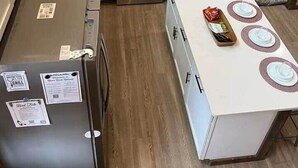 Een compacte keuken met witte kastjes, een centraal geplaatst fornuis en een eethoek met een tafel gedekt voor vier personen.