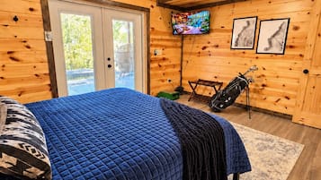 A bedroom with a bed, a ceiling fan, a television, and a door leading outside.