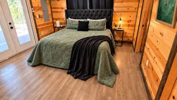 A bedroom with a bed, a ceiling fan, a nightstand, and a window with curtains.