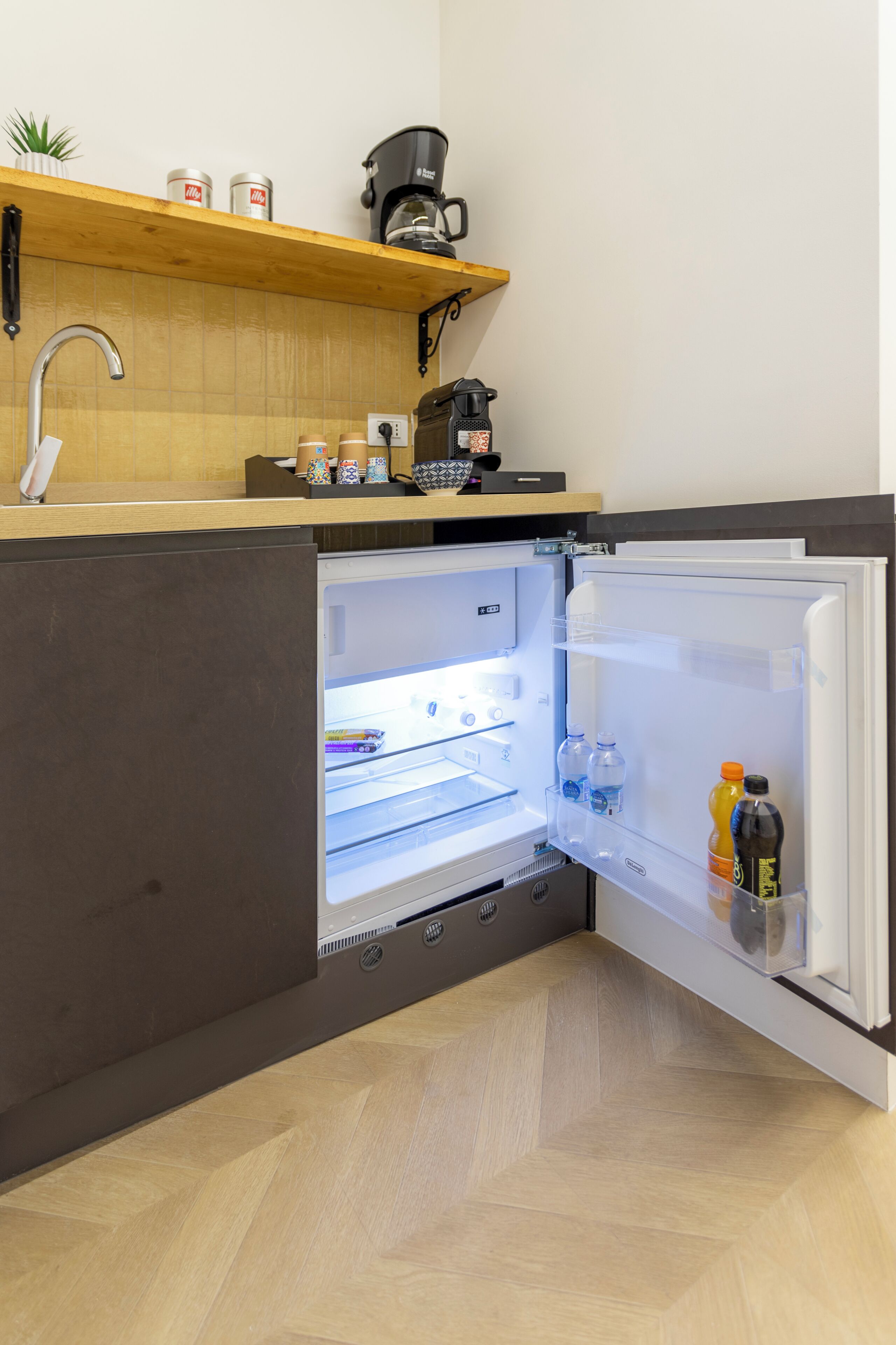 Eine moderne Küche mit einem eingebauten Kühlschrank, einer Kaffeemaschine und einem Regal mit Behältern.