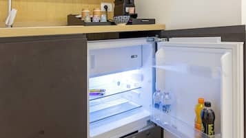 Une cuisine moderne équipée d’un réfrigérateur encastré, d’une machine à café et d’une étagère avec des récipients.