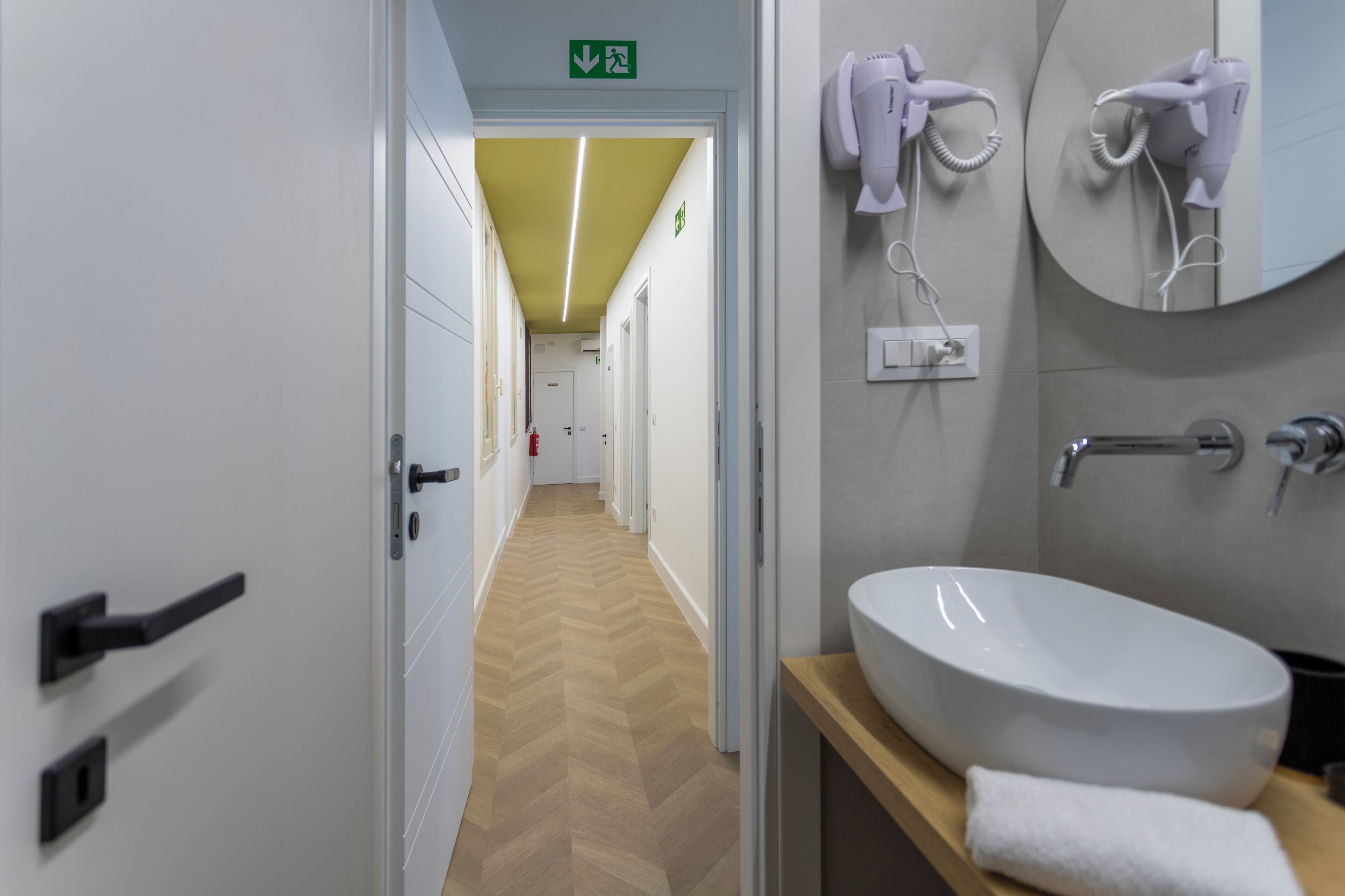 Un baño de hotel con lavamanos blanco, toalla y secador de pelo.