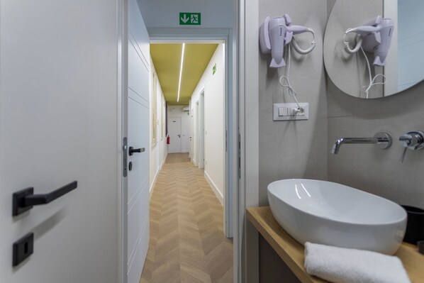 A hotel bathroom with a white sink, towel, and hairdryer. - Trastevere suites guest house  (Rome)