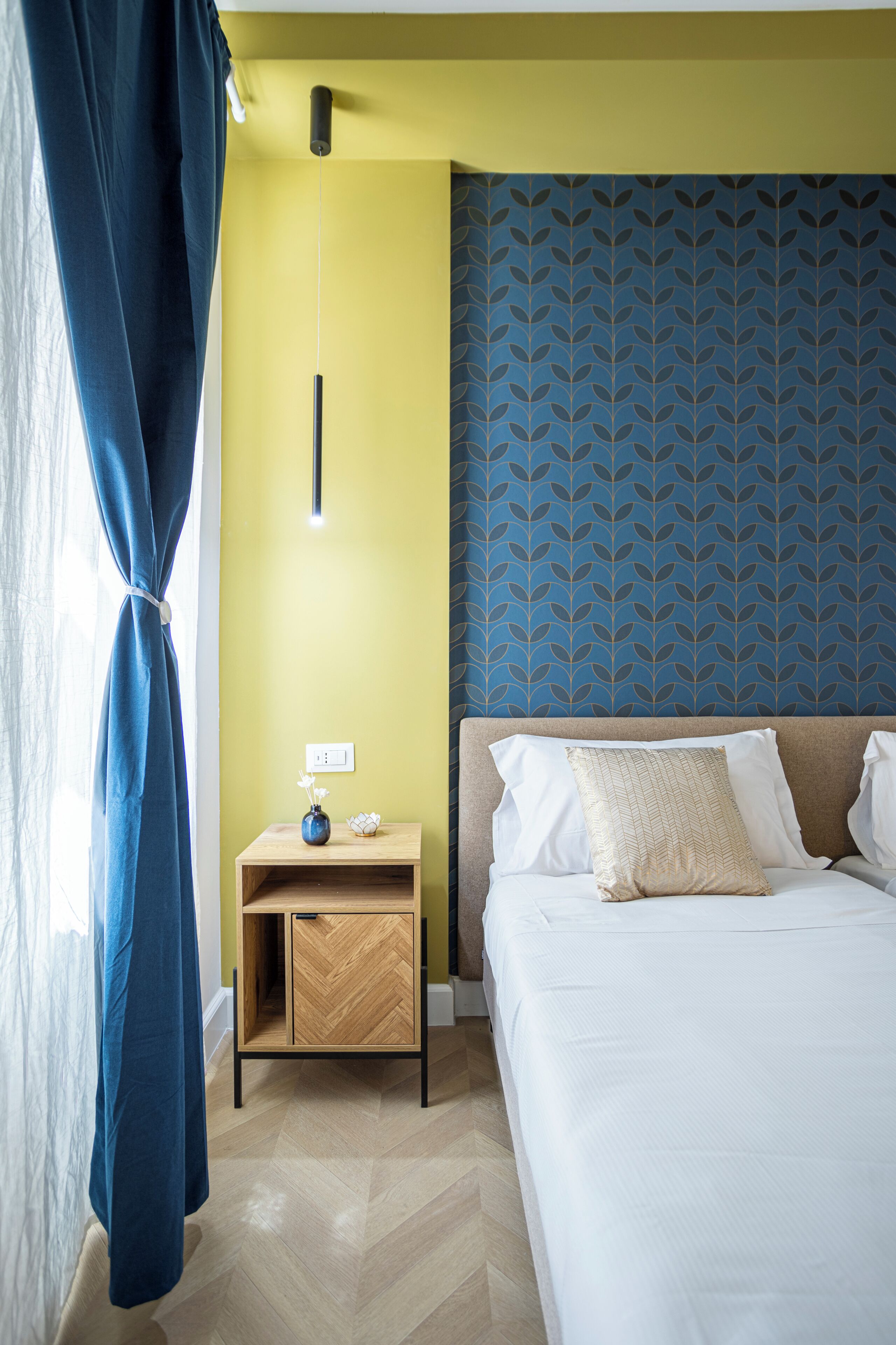 A hotel room with a bed, bedside table, and a nightstand.