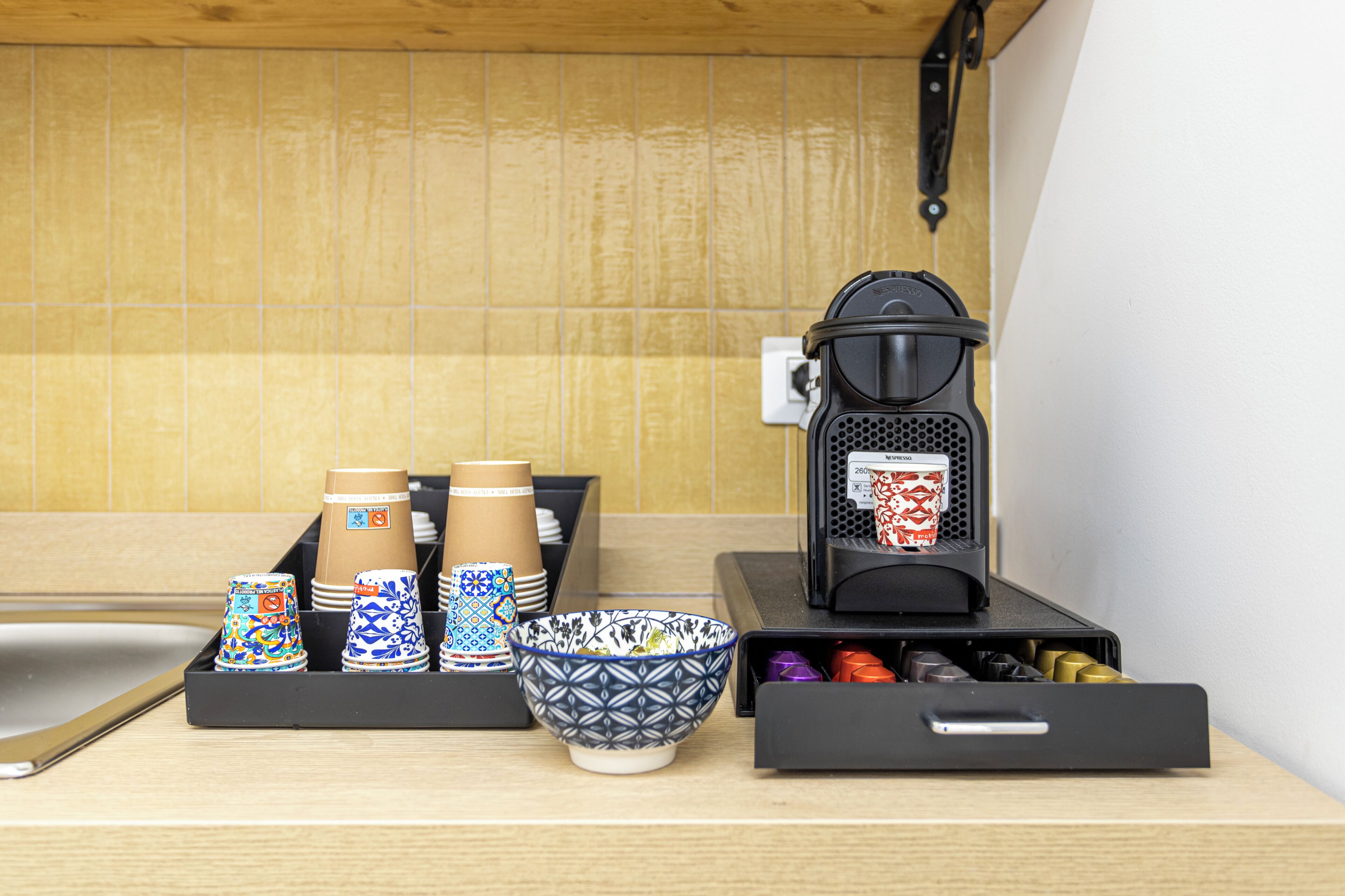 A kitchen counter with a coffee machine, a bowl, and a tray of cups.