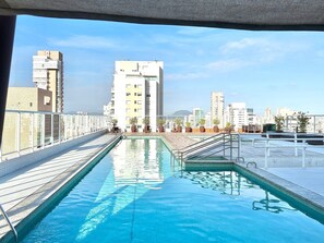 Una piscina en la azotea con vistas a la ciudad, rodeada de edificios.