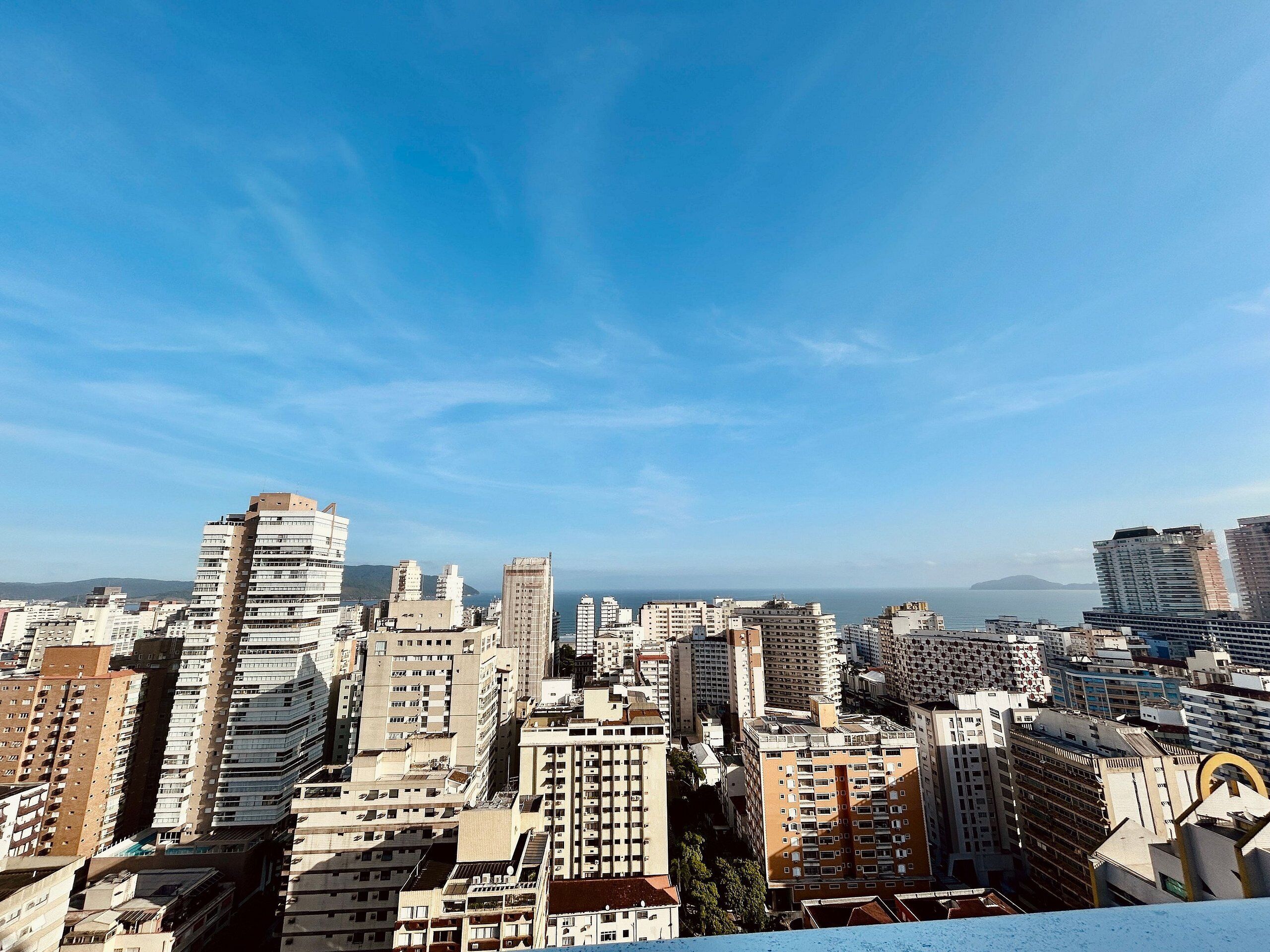 Un paisaje urbano con rascacielos, cielo despejado y montañas al lejano.