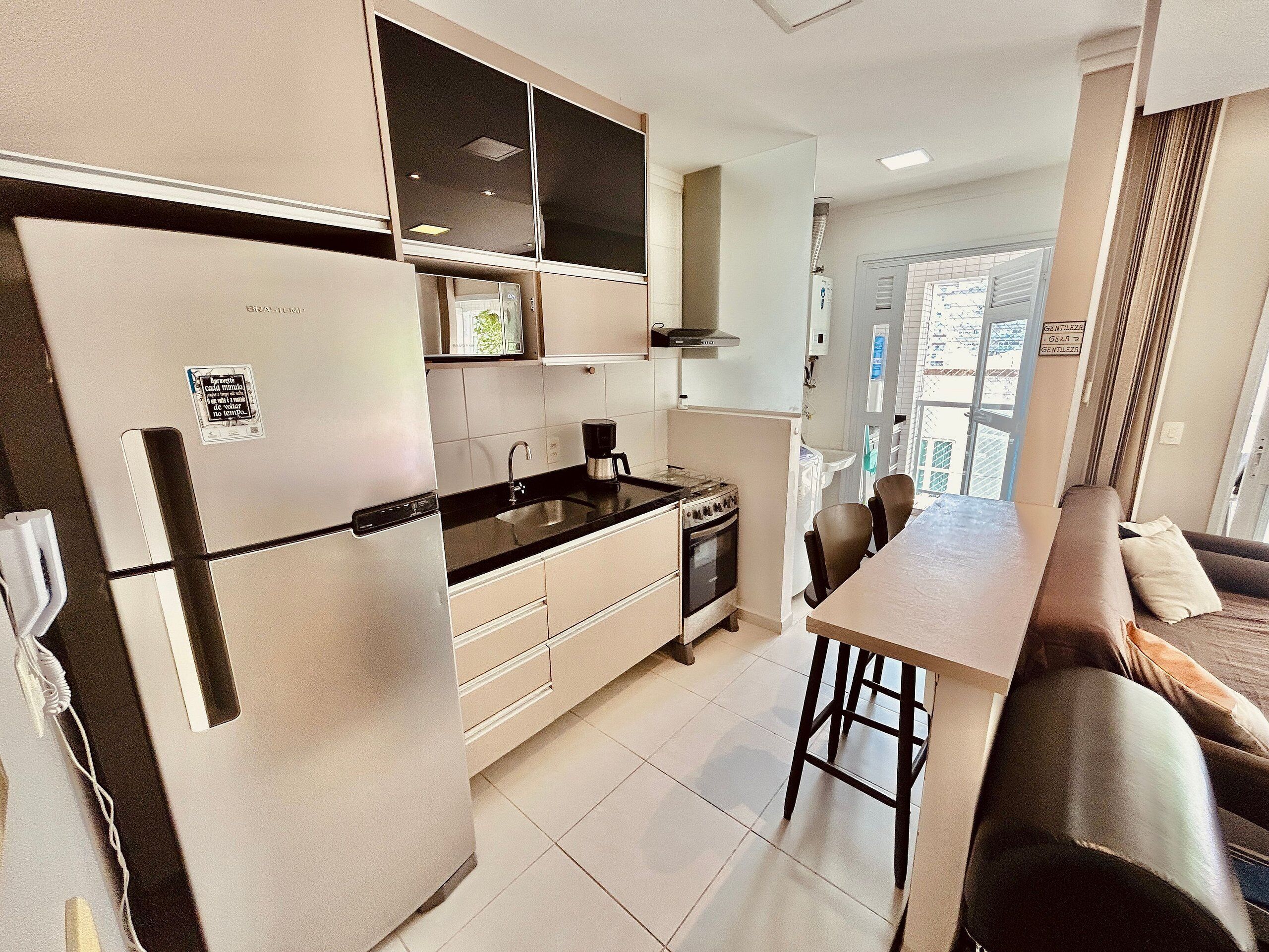 Una cocina moderna con refrigerador, estufa, lavaplatos y comedor con sillas.