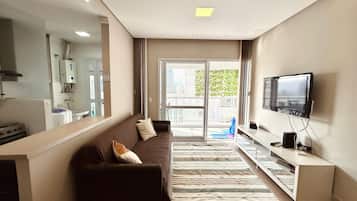 Una sala de estar moderna con sofá, televisión y vistas al exterior.