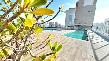 A rooftop pool with a clear view of the city skyline, surrounded by potted plants.