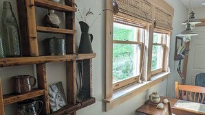 Et hyggeligt interiør med træhylder, et bord med en stol, et vindue med persienner og en hængende lampe.