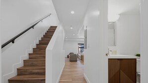 A staircase with wooden steps and a metal handrail, leading to a living area with a sofa and a coffee table. - Lovely Beachside 2-Bedroom Apartment (Santa Monica)