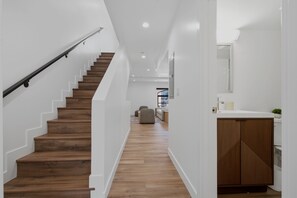 A staircase with wooden steps and a metal handrail, leading to a living area with a sofa and a coffee table. - Lovely Beachside 2-Bedroom Apartment (Santa Monica)
