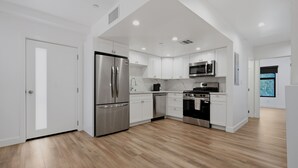 A modern kitchen with white cabinetry, stainless steel appliances, and a wooden floor. - Lovely Beachside 2-Bedroom Apartment (Santa Monica)