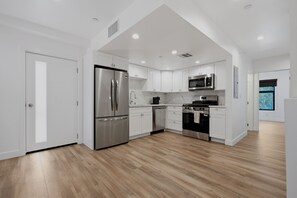 A modern kitchen with white cabinetry, stainless steel appliances, and a wooden floor. - Lovely Beachside 2-Bedroom Apartment (Santa Monica)