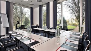 A conference room with a long table, chairs, a whiteboard, and large windows with a view of trees. - 4 Person Holiday Park Home in Kassel (Kassel)