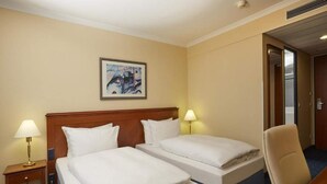 A hotel room with two beds, a desk, a chair, a painting on the wall, and a door to the right. - 4 Person Holiday Park Home in Kassel (Kassel)