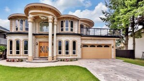 A large, two-story house with a curved facade, multiple windows, and a garage.