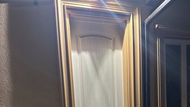 Eine weiße Tür mit schwarzem Griff, einer Metall-Schutzleiste am Boden und einem kleinen Fenster darüber.