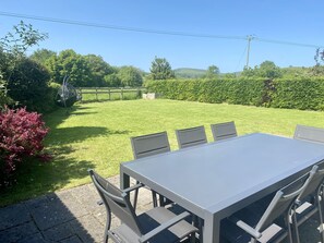 A patio with a table and chairs, surrounded by a well-maintained lawn and hedges. - Byre House (Sleeps 6) - Sutton Waldron , Shaftesbury sleeps 6 guests  in 3 bedrooms (Blandford)
