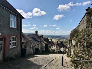 A cobblestone street in a historic village with stone buildings, a narrow path, and a clear sky. - Byre House (Sleeps 6) - Sutton Waldron , Shaftesbury sleeps 6 guests  in 3 bedrooms (Blandford)