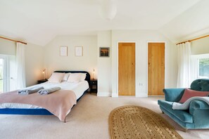 A bedroom with a bed, bedside tables, a sofa, a rug, and two doors. - Byre House (Sleeps 6) - Sutton Waldron , Shaftesbury sleeps 6 guests  in 3 bedrooms (Blandford)