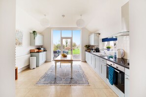 A modern kitchen with a central island, white cabinetry, and a view to the outdoors. - Byre House (Sleeps 6) - Sutton Waldron , Shaftesbury sleeps 6 guests  in 3 bedrooms (Blandford)