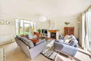 A spacious living room with a sofa set, a fireplace, and a television. - Byre House (Sleeps 6) - Sutton Waldron , Shaftesbury sleeps 6 guests  in 3 bedrooms (Blandford)