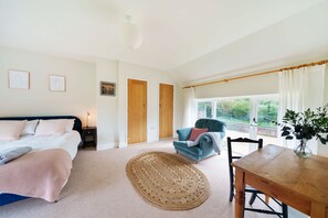 A bedroom with a bed, bedside table, lamp, and a view of the outdoors through a window. - Byre House (Sleeps 6) - Sutton Waldron , Shaftesbury sleeps 6 guests  in 3 bedrooms (Blandford)