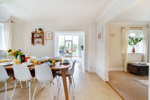 Ein helles Esszimmer mit gedecktem Frühstückstisch, Stühlen und Blick auf den Garten durch die Tür.