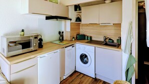 Cocina compacta con microondas, tostadora, fregadero y lavadora.