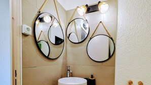 Un baño con un espejo redondo, un lavamanos y un inodoro.