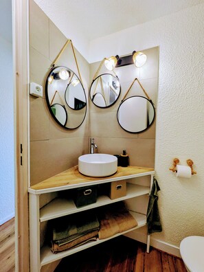 A bathroom with a round mirror, a sink, and a toilet. - La Casa Soléa, a charming apartment near the beaches (St. Cyprien) (Saint-Cyprien)