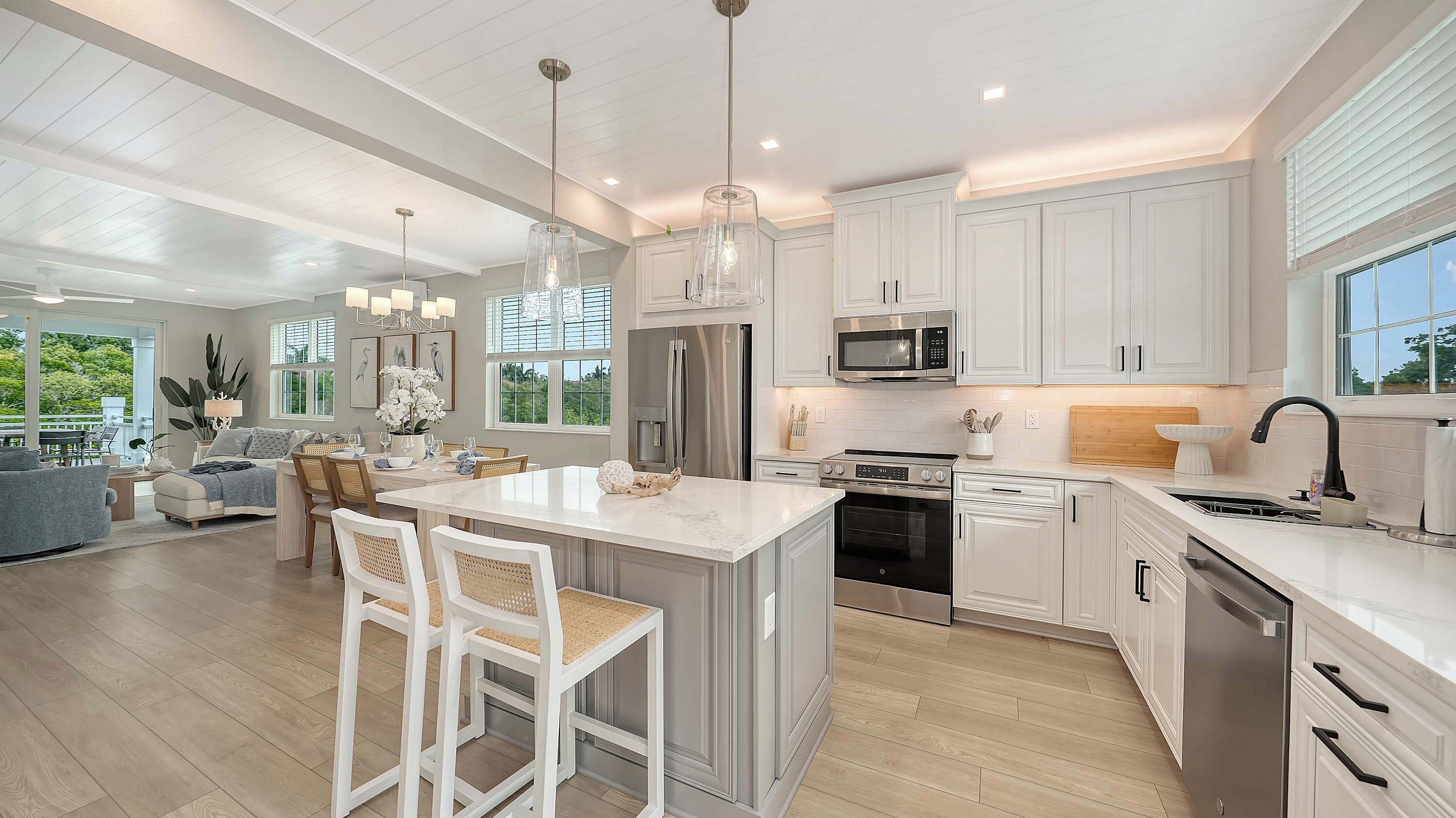 A modern kitchen with white cabinetry, stainless steel appliances, and a large island with bar stools.