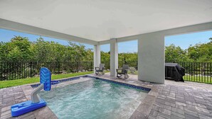 A swimming pool with a hot tub, surrounded by a covered patio area with chairs and a grill. - Luxury Waterfront Home with Private Dock and Pool Manatee Cove at Hunters Point (Cortez)
